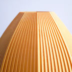 Close-up of a textured golden 3d print vase against a light blue background