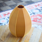 Golden 3d printed vase with a textured surface on a woven mat