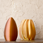 Two 3d printed vases on a wooden surface with a light creame background