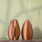 Two copper-colored vases on a wooden surface with a light blue background