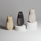 Three vases of different colors on cylindrical stands against a gray background