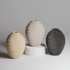 Three textured ceramic vases in beige, gray, and black on a light gray background