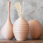 Three decorative vases with unique designs on a wooden surface against a light background