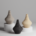 Three textured vases in black, beige, and gray on a gray background
