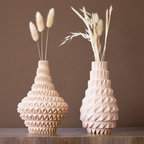 Two geometric-patterned vases with dried plants on a light blue background