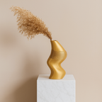 Gold decorative vase with wavy design on a white pedestal against a beige background