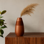 Brown vase with dried pampas grass on a wooden surface against a beige wall
