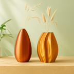 Two decorative vases with dried plants on a wooden surface and light green background