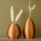 Two brown vases with dried plants on a wooden surface and green background